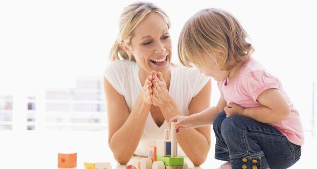 Mother and daughter indoors playing and smiling