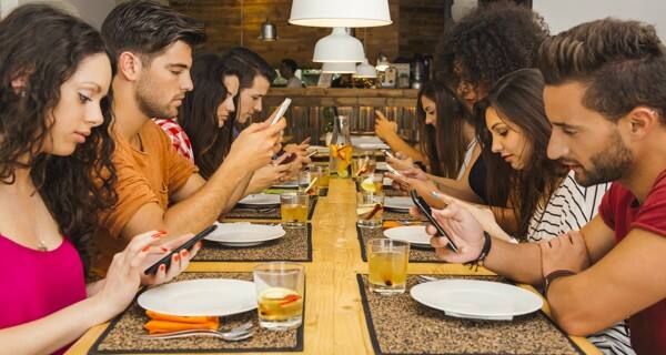 Gadget addiction, friends at dinner dependent on smartphones Stock