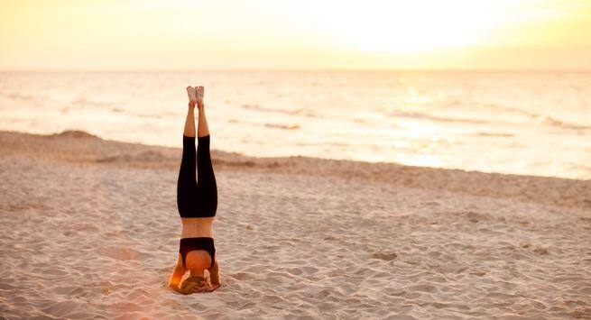 Women friends, beach yoga and smile in morning with stretching legs for  health, wellness and training. Black woman, exercise group and motivation  for teamwork with balance, peace and support by sea |